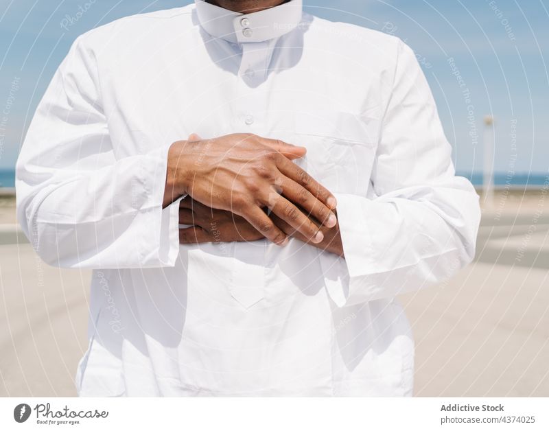 Muslim man praying on beach muslim arab islam religion tradition culture rug ritual worship holy male ethnic authentic sand arid desert blue sky robe faith