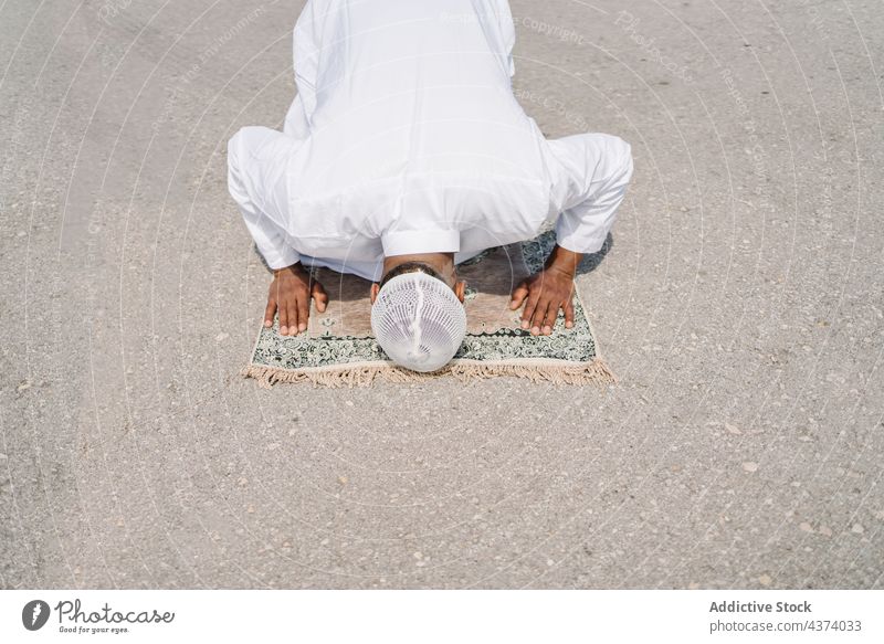 Islamic man praying on mat on beach muslim arab islam religion kneel bow tradition culture rug ritual worship holy male ethnic ground bend authentic sand arid