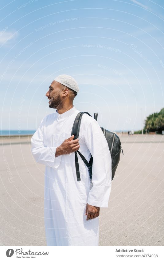 Muslim man with backpack on beach arab muslim islam rest summer weekend adjust smile happy tradition male positive joy holiday ethnic glad content cheerful