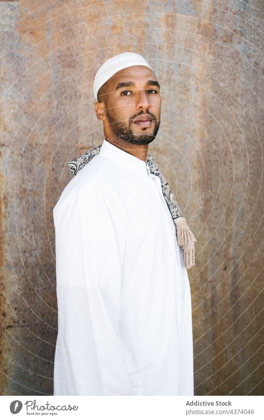 Muslim man in traditional clothes culture wall grunge religion garment appearance portrait exterior male building islam muslim ethnic arab shabby apparel cap