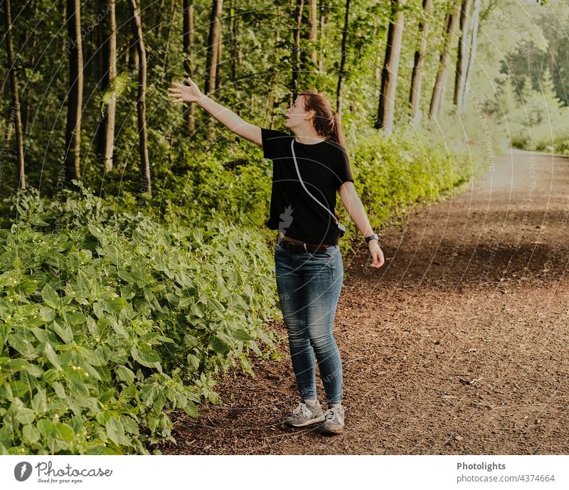 Young woman on a forest path throws a green branch into the bushes Woman Forest Twig Throw away Indicate Interpret Green Brown Nature Environment Tree Plant