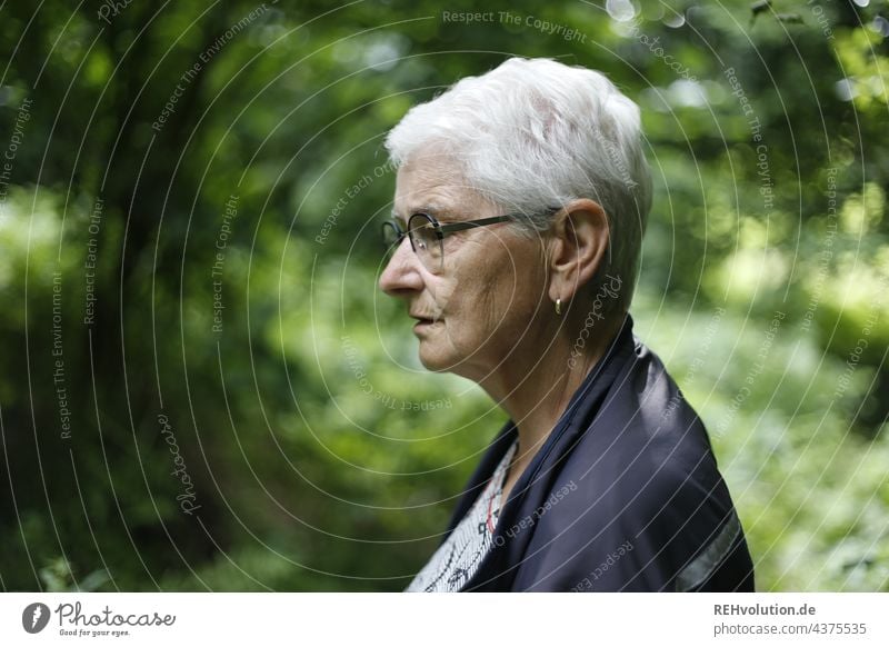 Profile of a senior woman in the forest Senior citizen 60 years and older Female senior Grandmother Gray-haired naturally White-haired Woman portrait Authentic