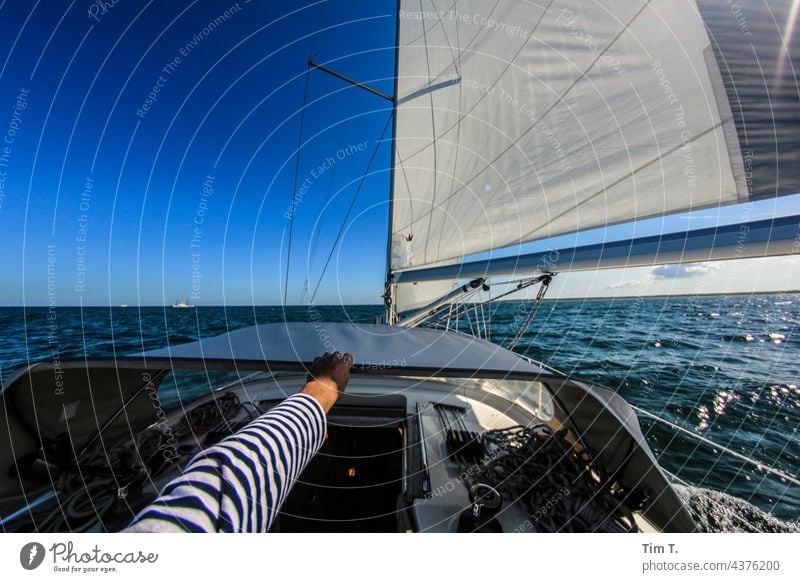 one hand holds on to the ship Sailor Seaman Hand arm Striped sweater Human being Sailing ship Watercraft Sailboat Navigation Sky Ocean Yacht Vacation & Travel