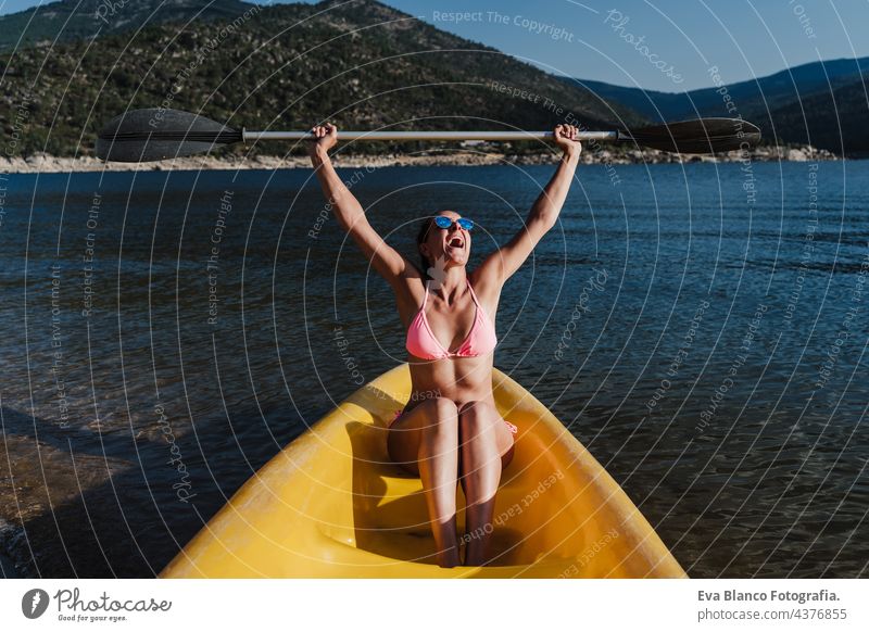 happy caucasian woman holding oar sitting on yellow canoe in lake during sunny day. summer time. Sports, adventure and nature rowing swim wear sports holidays