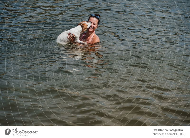 caucasian woman and cute jack russell dog swimming in lake and having fun together. Dog licking owner. vacation and relax concept nature summer love