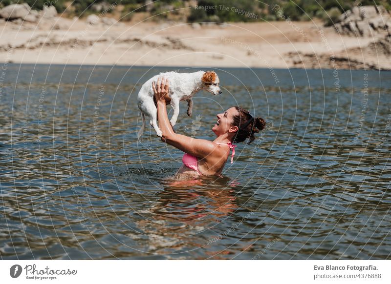 caucasian woman and cute jack russell dog swimming in lake and having fun together. vacation and relax concept nature summer love togetherness hot kiss hug