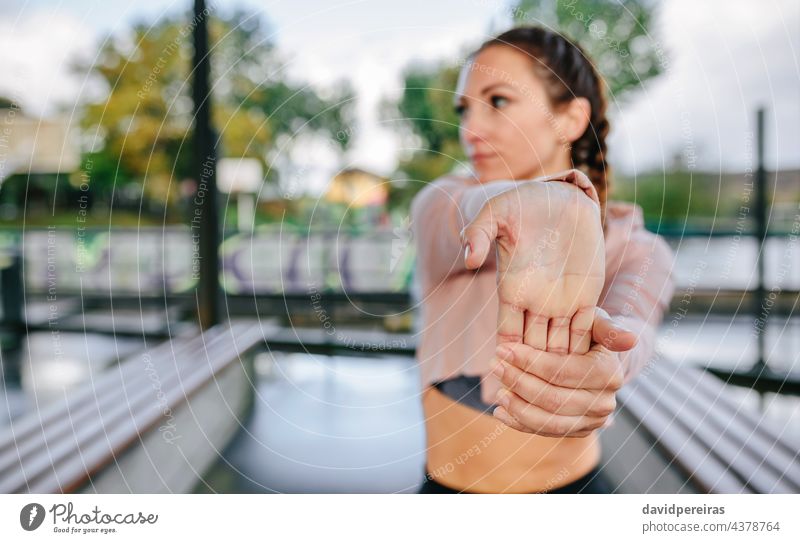 Young female athlete stretching hands and wrists outdoors fingers warmup woman copy space foreground focus training fitness young waist up workout healthy
