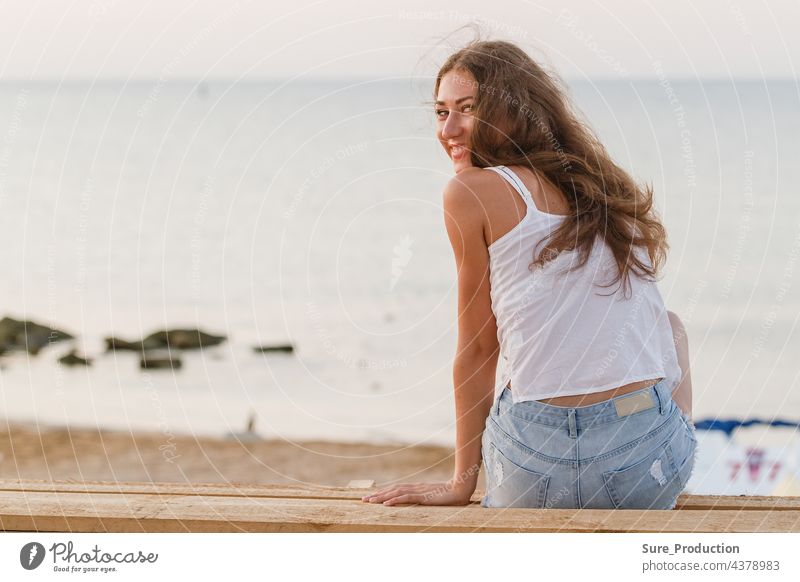 adorable young woman on the beach in the rays of the rising sun sexy girl curly brunette slim white portrait pretty lady flying hair beautiful hipster summer