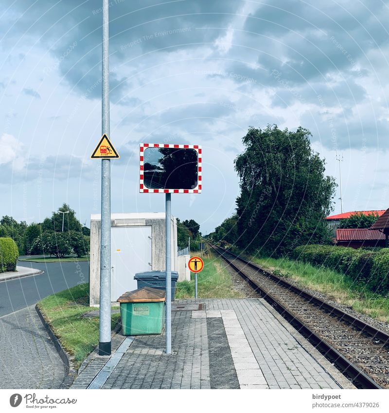 endstation of train,a mirror and warning labels small village northsea way trainstation tracks deutsche bahn waiting tree cloudy weather Warning label