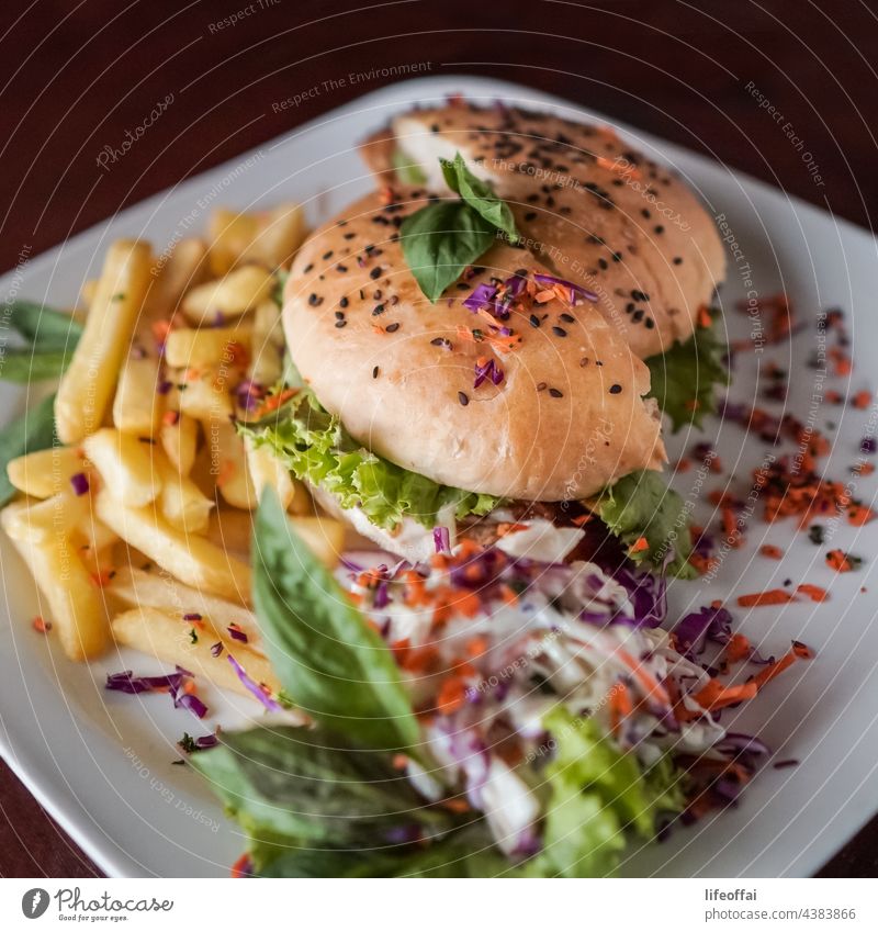 Chicken burger with fries and mayo sauce and vegetable dressing on a table cheeseburger holding lettuce unhealthy fast photography woman horizontal human
