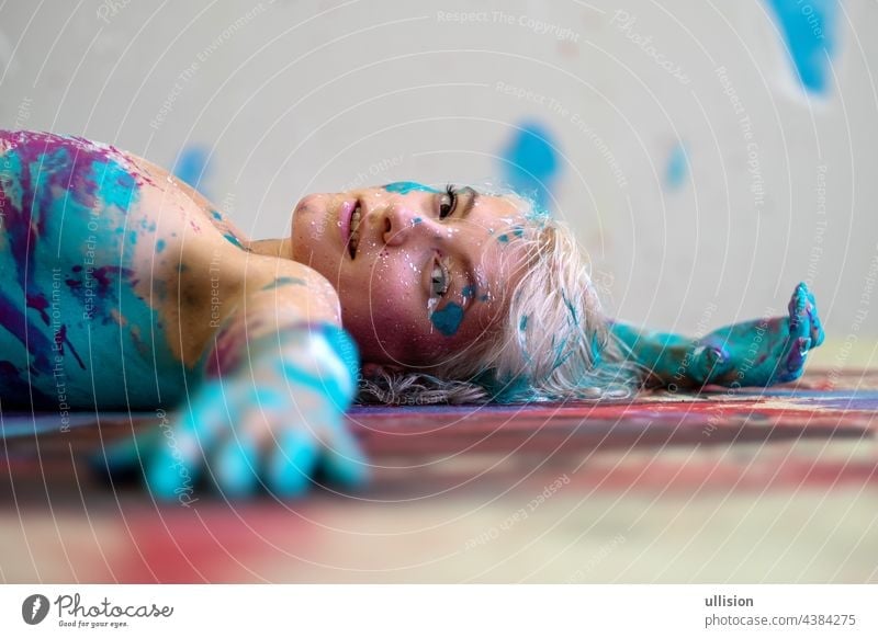 direct view Portrait and her hands and arms of a sexy young blonde woman in turquoise and magenta color, painted, lies decorative, Creative expressive abstract body painting art, copy space
