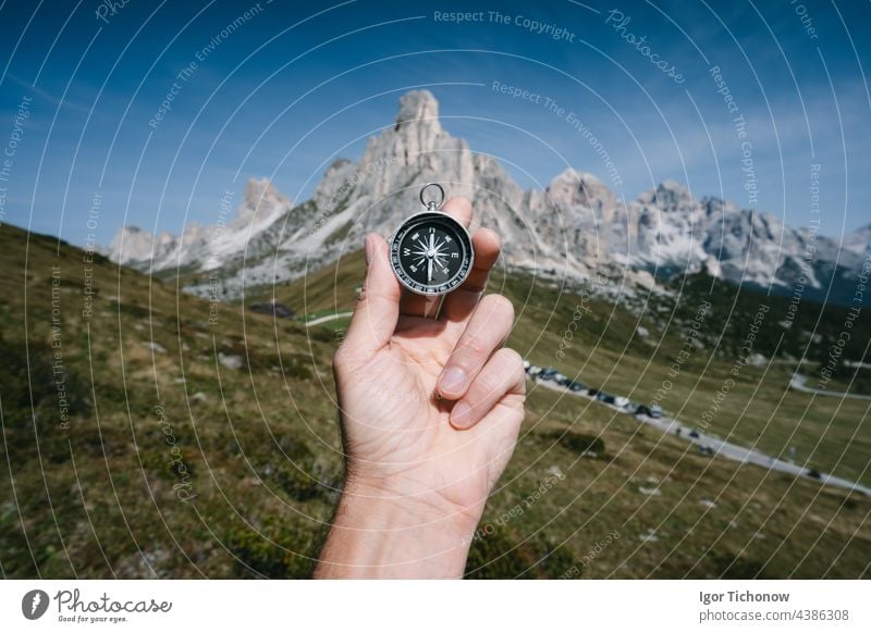 Hand holding compass against Passo Giau mountains in background in Dolomites alps, Italy. Travel adventure concept dolomites passo giau italy tourism peak goal