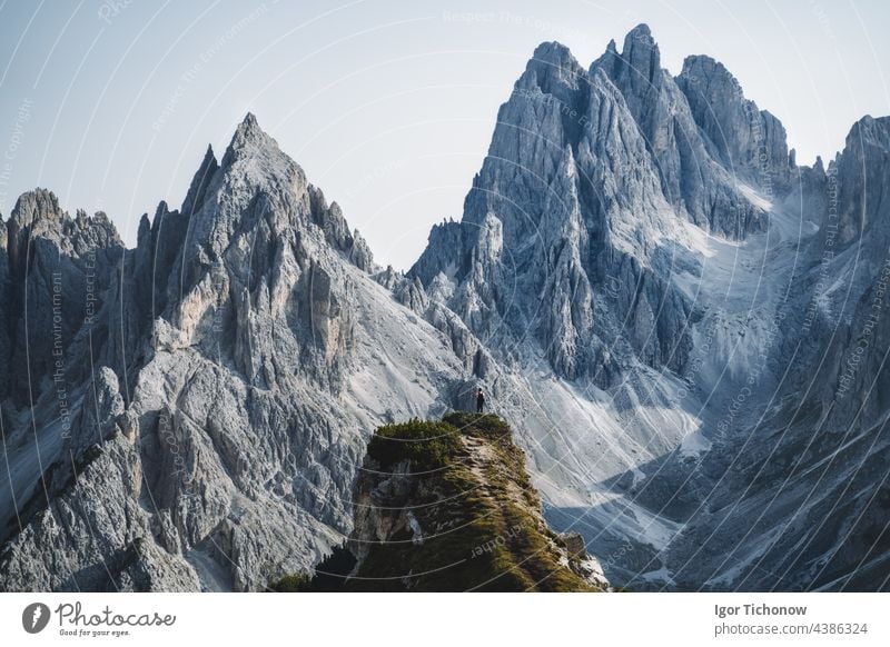 Man hiker standing and admiring stunning beauty of impressive jagged peaks of Cadini di misurina mountain group in Dolomites, Italy, part of Tre Cime di Levaredo national park