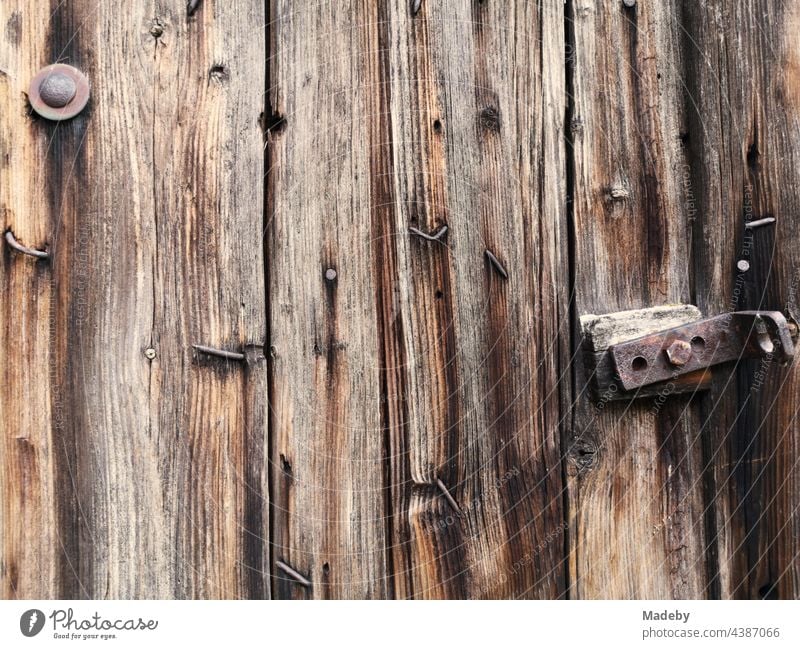 Crooked nails and rusty fittings in an old brown wooden stable door on a farm in Rudersau near Rottenbuch in the Weilheim-Schongau district of Upper Bavaria