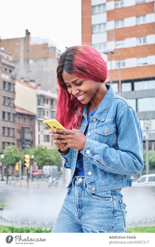 Funky ethnic woman with smartphone on street message style dyed hair color urban informal hipster female young black african american millennial modern