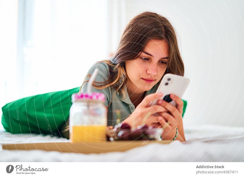 Young woman using smartphone during breakfast at home morning online browsing internet communicate young female student mobile gadget device surfing