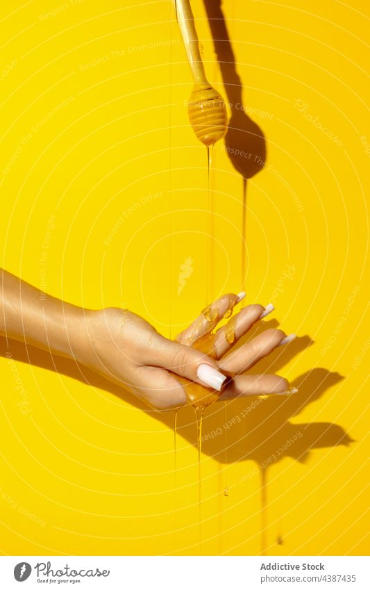 Crop model with honey flows on hand woman fluid sweet viscous treat tasty natural shade bright organic delicious colorful fresh shadow demonstrate vivid