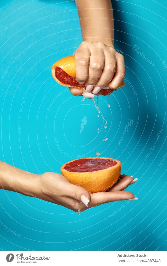 Woman squeezing fresh juicy grapefruit hand squeeze juice half natural healthy citrus female vitamin ripe organic food tropical red cut manicure nail bright