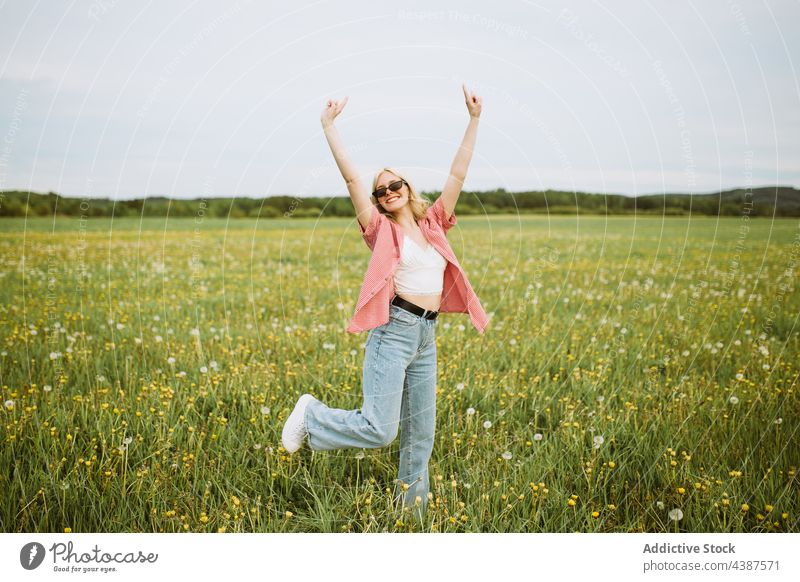 Cheerful woman showing horn gesture in summer field rock sign rock and roll cheerful meadow female freedom carefree style happy symbol rocker trendy content