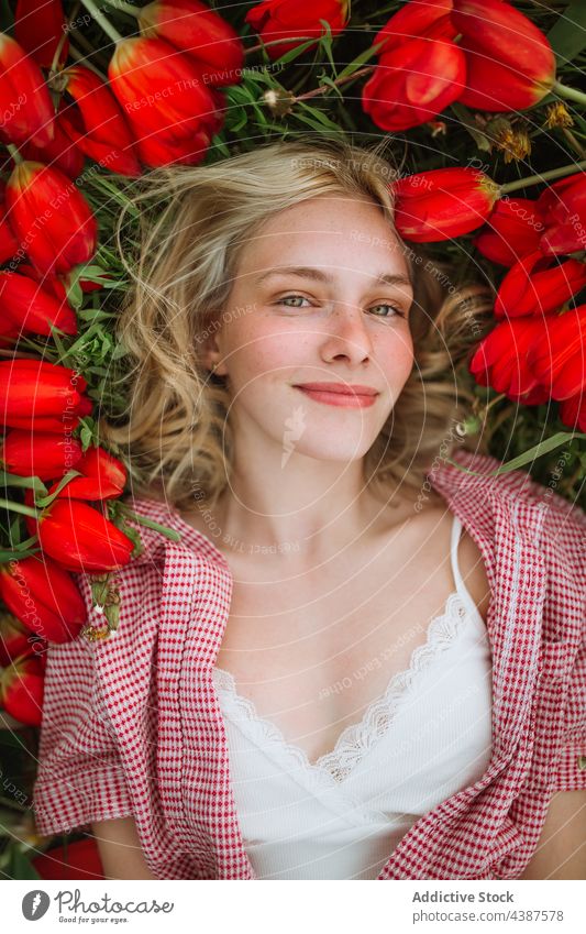 Happy woman lying in meadow with red tulips bloom field flower bunch smile blossom female nature happy floral tender feminine carefree charming bright summer