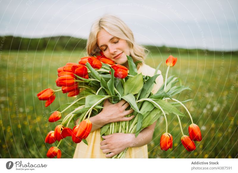 Gentle woman with bouquet of red tulips in field flower summer bunch meadow tender smile female content bloom blossom romantic young nature countryside flora
