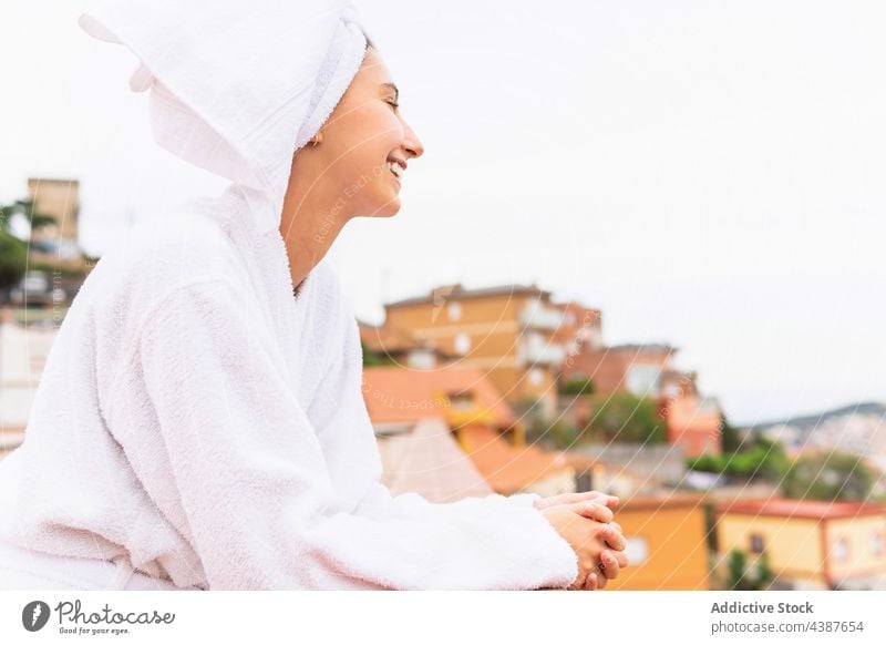 Cheerful female resting on balcony after shower woman skin care routine weekend hygiene smile morning young cheerful procedure spa towel bathrobe relax treat