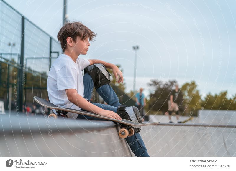 Skateboarder sitting on ramp in skate park boy skater teen skateboard urban hipster teenage serious hobby activity cool individuality recreation focus