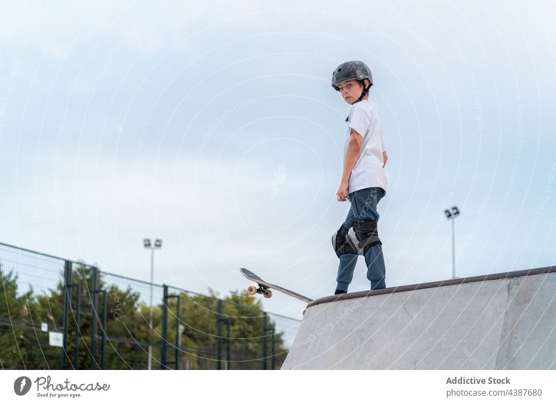 Teen boy riding skateboard in skate park skater ride teenage activity skill energy stand hobby urban move hand on waist action active serious determine summer