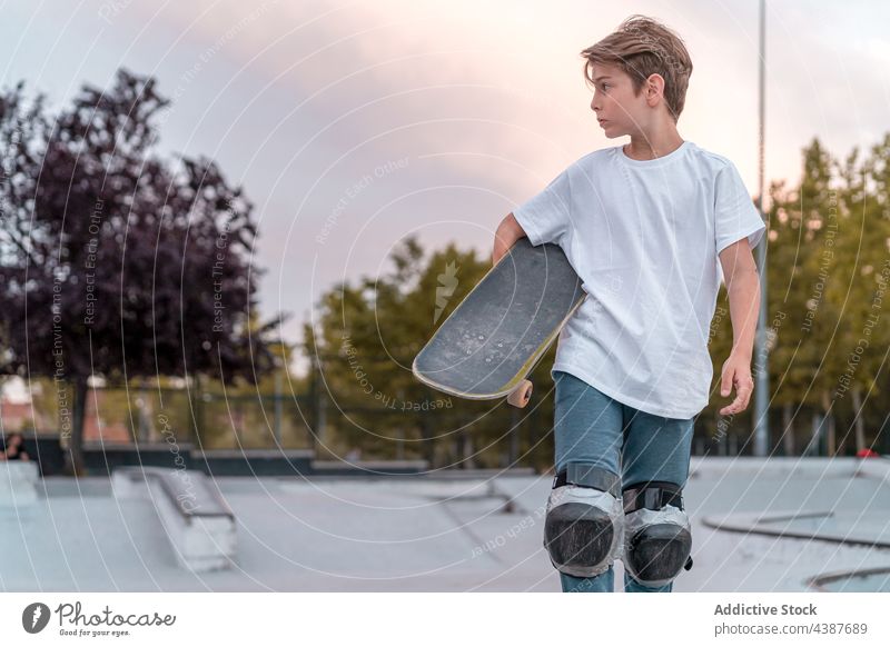 Teen boy with skateboard in skate park skater teenage hobby urban ramp activity cool hipster individuality recreation serious focus concentrate trendy protect