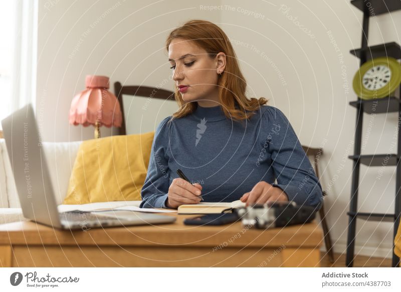 Woman taking notes and preparing for recording podcast woman radio host prepare write take note notebook microphone female headphones broadcast laptop home