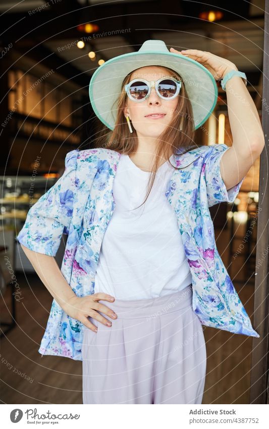 Smiling woman in hat against building with brick wall smile fashion style sunglasses friendly sincere town portrait rough stylish wear ornament garment