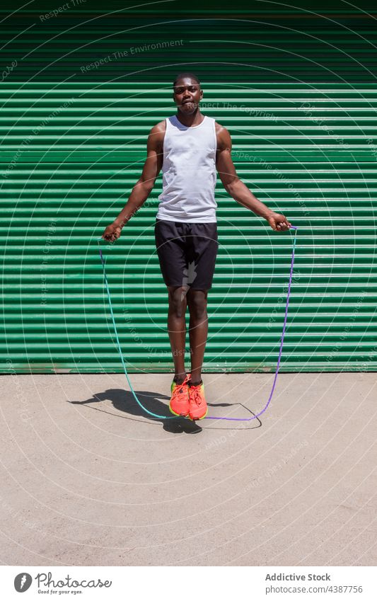 Black fit sportsman jumping rope during training black skip cardio exercise workout athlete city male ethnic african american summer activity vitality wellbeing