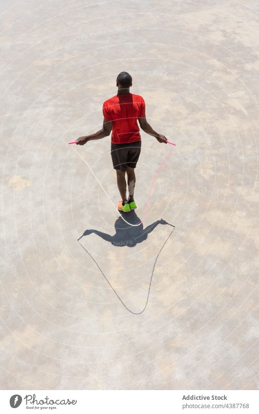 Unrecognizable black sportsman jumping rope on sports ground training exercise skip workout athlete active male ethnic african american activity fit energy