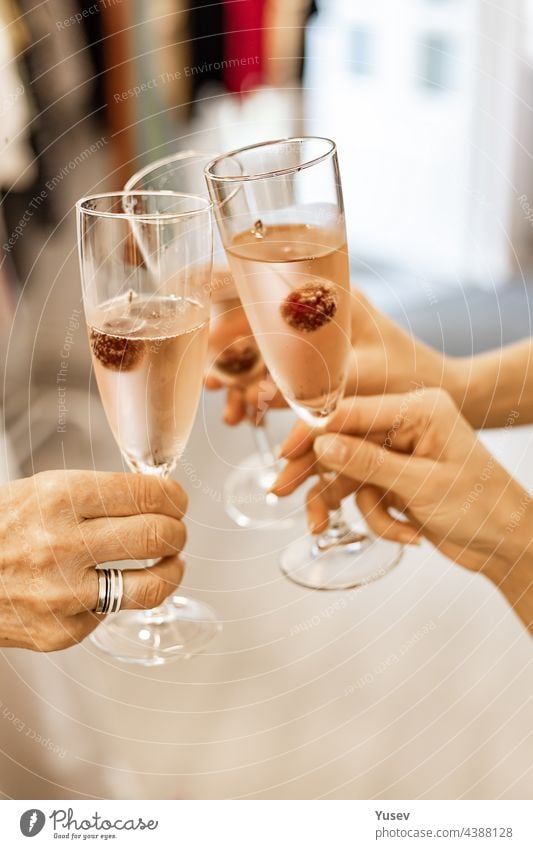 Beautiful female hands are holding glasses of champagne or rose wine. Close-up. Women clink glasses. New Years celebration, event or party. Soft focus. Human hands. Vertical shot