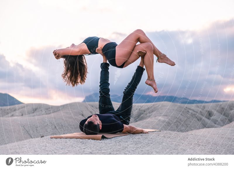 Flexible couple practicing acro yoga in sunset acrobatic balance support partner together mountain sky relationship evening romantic freedom tranquil practice