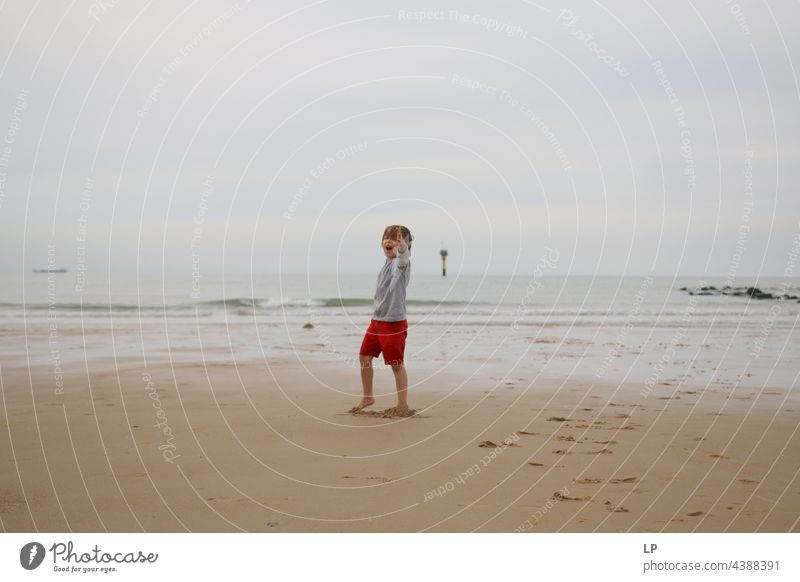 child alone on the beach pointing an arm towards the camera positive emotion smile Ocean Beach Risk Longing Individual Isolated Single Abstract Movement Flow