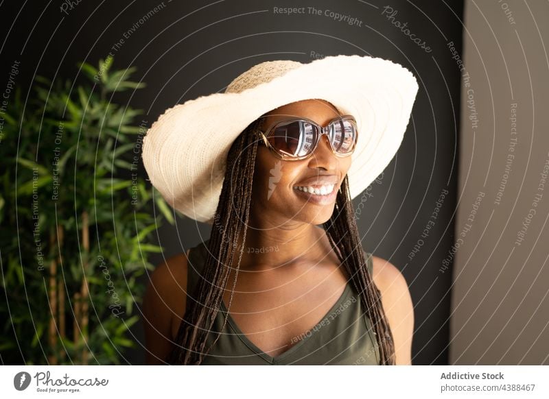 Cheerful stylish black woman in sunhat and sunglasses style trendy summer outfit straw hat cheerful happy female ethnic african american positive confident home