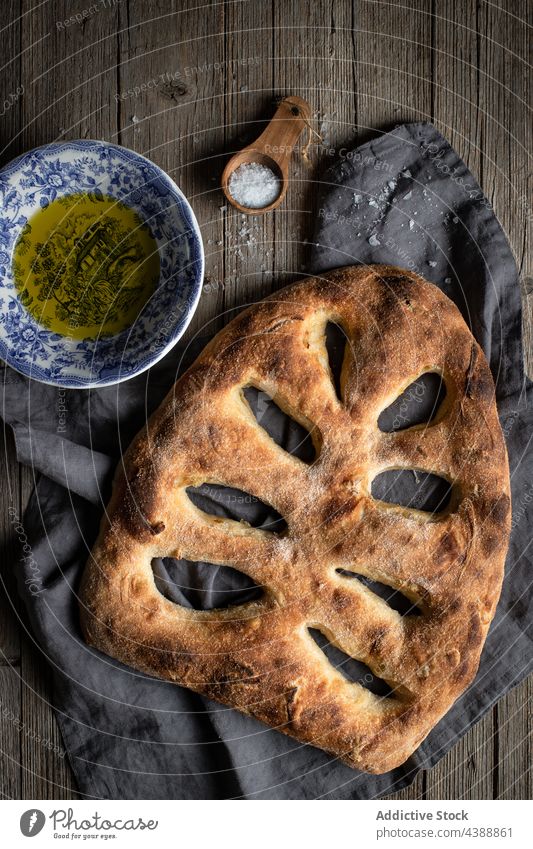 Baked fougasse bread on table with salt and oil baked loaf tradition bakery delectable homemade delicious fresh tasty spoon bowl napkin material fabric food