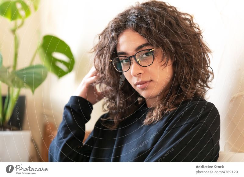 Young woman in eyeglasses resting at home curly hair young portrait eyewear style millennial female ethnic hispanic spectacle lifestyle gaze cozy comfort chill