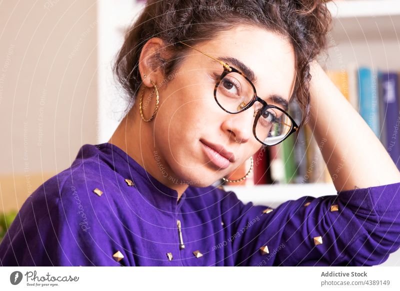 Ethnic woman in glasses looking at camera eyeglasses style portrait at home eyewear young trendy human face stare female ethnic hispanic brunette thoughtful