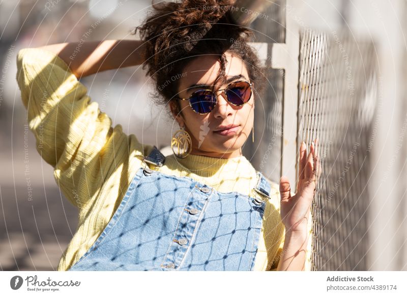 Stylish young woman in sunglasses style trendy fashion accessory modern urban sunlight millennial female eyewear denim yellow curly hair hispanic ethnic shadow