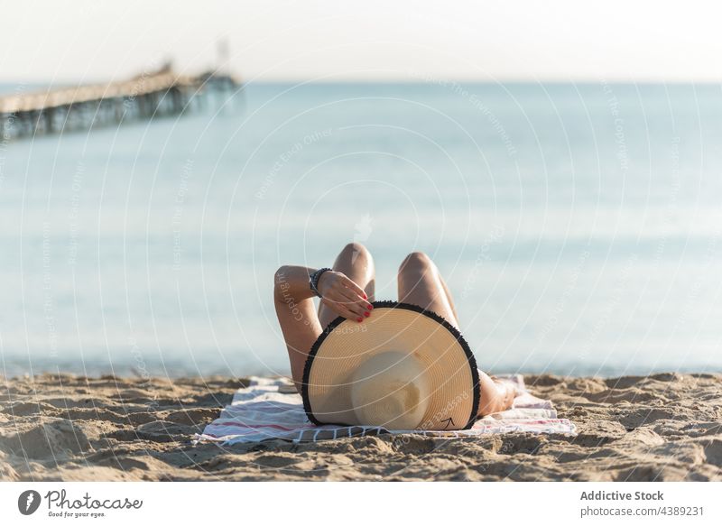 Unrecognizable woman in sunhat lying on beach near sea sunbath summer suntan straw hat vacation seaside holiday female playa de muro alcudia mallorca spain rest