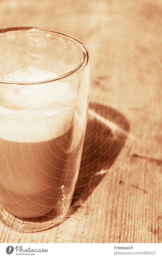 Latte macchiato glass on wooden table with shadow Beverage Shadow play Lunch hour Summer free time Break vacation Vacation mood Sunlight To enjoy