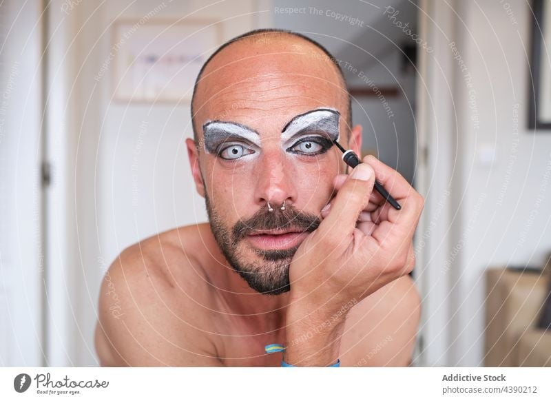 Bearded man applying makeup on eyes drag queen transgender eyeliner eyebrow cosmetic visage lens male piercing beard appearance concept alternative unusual