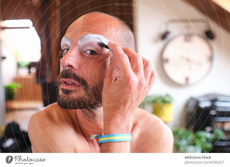 Bearded man applying drag queen makeup bisexual eyebrow cosmetic gender visage transgender male piercing beard bracelet appearance concept alternative unusual