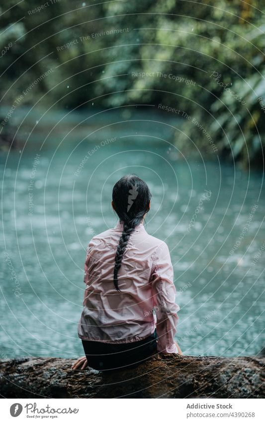 Woman in wet shirt sitting near river woman alone traveler nature relax solitude adventure forest tranquil female tourism jungle vacation tropical journey