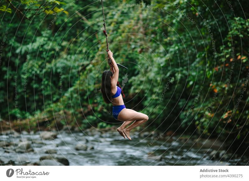 Woman on rope jumping over river woman bungee forest adventure activity travel stream female young active extreme nature vacation summer holiday tourism