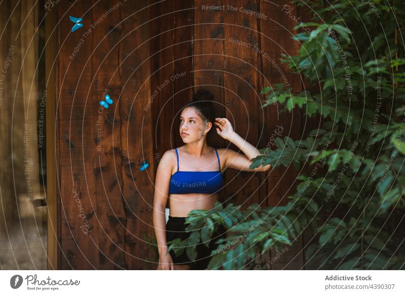 Young woman standing near wooden wall with butterflies butterfly nature house summer tropical travel blue female young vacation swimwear color holiday tourism