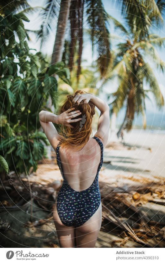 Slim woman in swimsuit on tropical beach palm summer redhead vacation travel nature seashore holiday paradise enjoy seaside ocean female coast exotic idyllic
