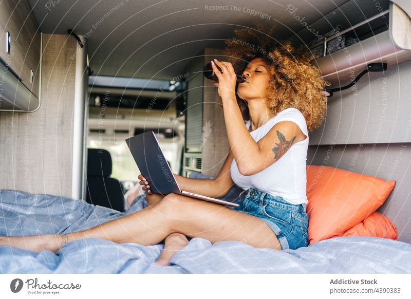 Ethnic woman chilling in camper van laptop using rest beer summer traveler holiday female african american black ethnic drink young vacation curly hair movie